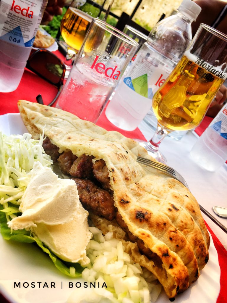 Cevapi is a traditional grilled meat sausage served with onions, bread, and yogurt in Mostar, Bosnia