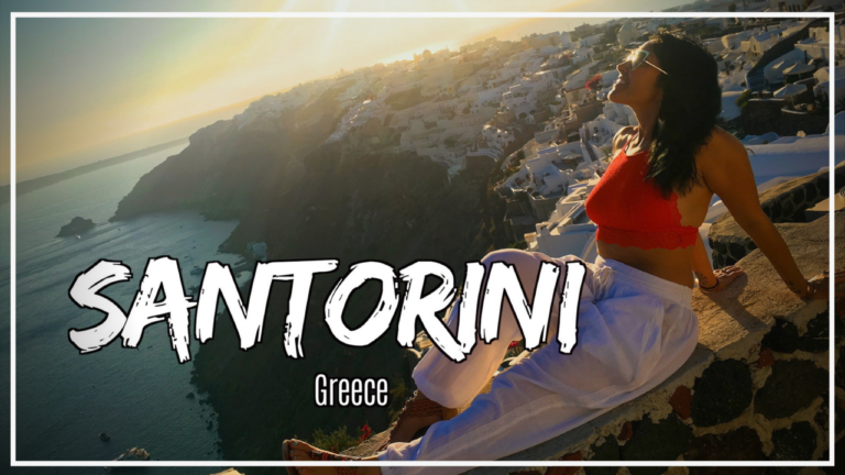 Woman sitting on the wall in front of a Santorini Greece sunset