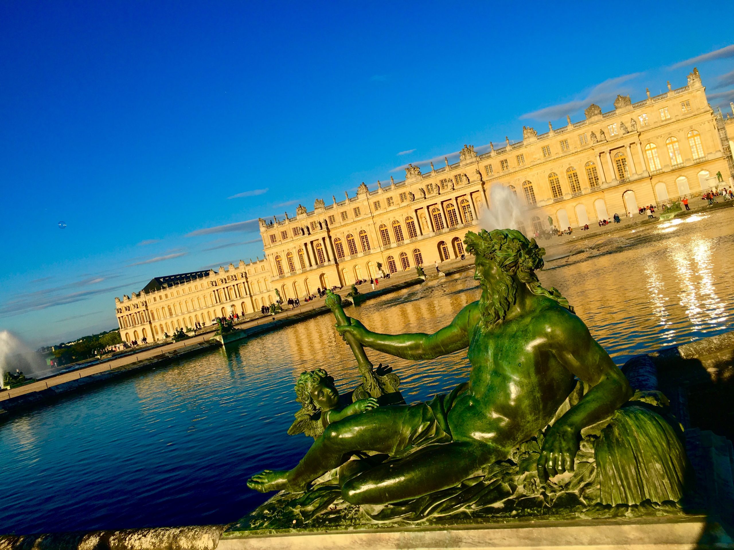 Statues in the garden of the palace of versailles at sunset